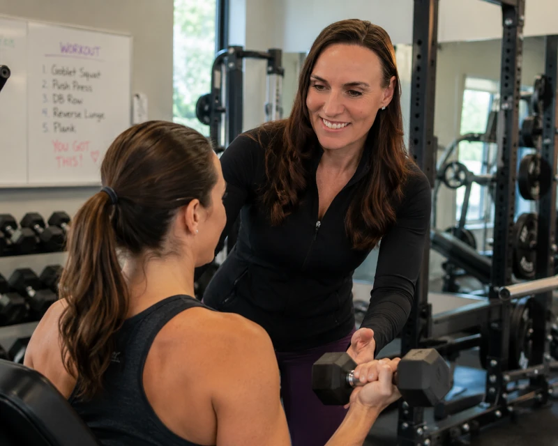 Veronica guiding a client on the cable machine with hands-on coaching